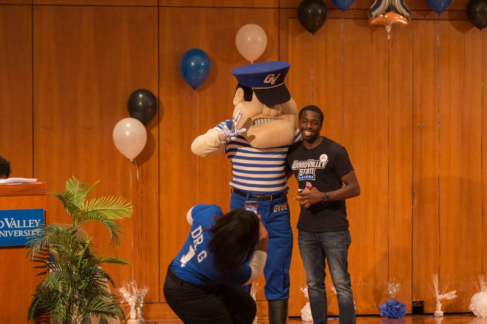 Image of male student taking picture with Louis the Laker, GVSU Mascot